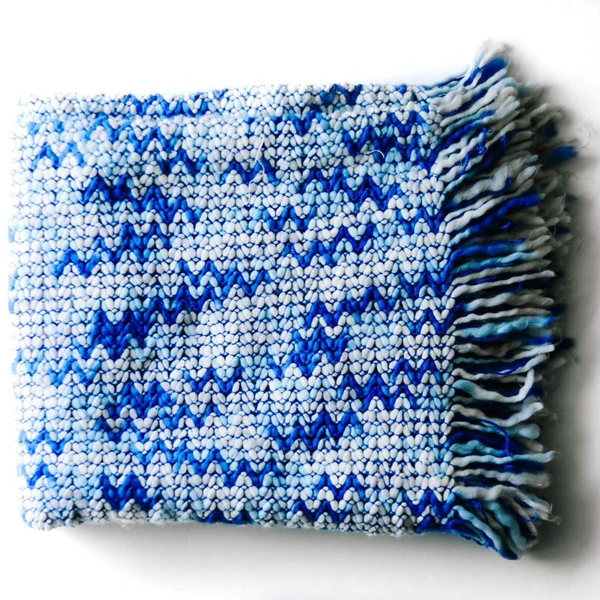 A blue throw blanket with a woven zig zag pattern
