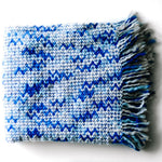 A blue throw blanket with a woven zig zag pattern