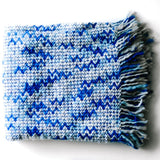 A blue throw blanket with a woven zig zag pattern