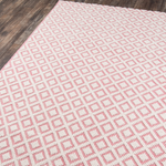 Pink and ivory diamond patterned flatweave area rug displayed on a wood floor, modern geometric woven area rug.
