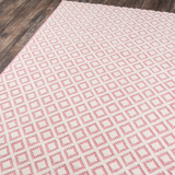 Pink and ivory diamond patterned flatweave area rug displayed on a wood floor, modern geometric woven area rug.