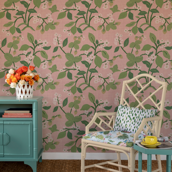 a chair and chest of drawers against a background of green, white and pink wallpaper with strawberry and lemon motifs. 