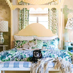 a yellow four poster canopy bed with floral bedding and a black pug dog on a bench at the end.