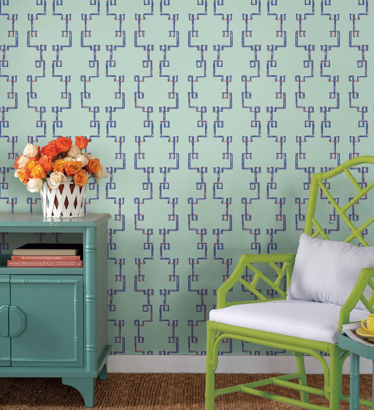 a green chair and blue chest agains a wall of blue removable wallpaper featuring a navy blue geometric trellis motif. 