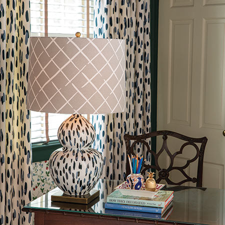 A blue and white table lamp with a blue and white base and beige lampshade in a cosy study. 