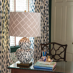 A blue and white table lamp with a blue and white base and beige lampshade in a cosy study. 