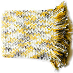 A yellow throw blanket with a tan and yellow woven zig zag pattern