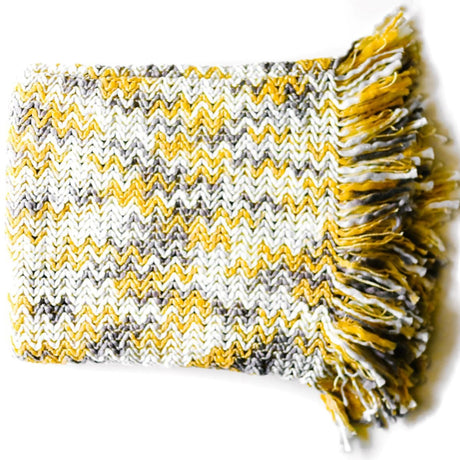 A yellow throw blanket with a tan and yellow woven zig zag pattern 