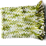 A white and green throw blanket with a woven zig zag pattern