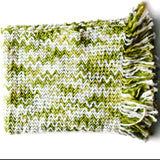 A white and green throw blanket with a woven zig zag pattern