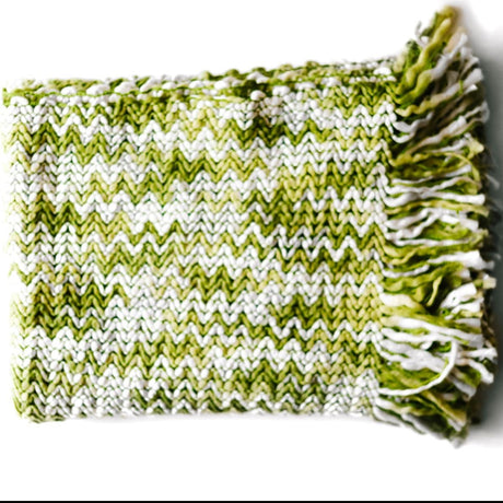 A white and green throw blanket with a woven zig zag pattern 