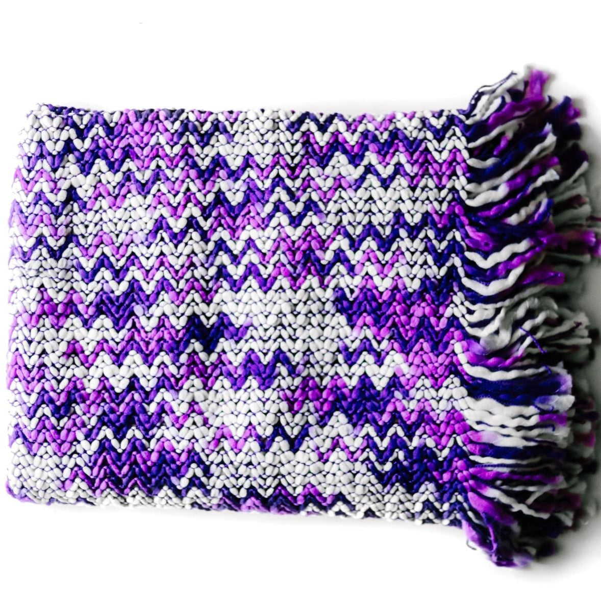A white and purple throw blanket with a woven zig zag pattern