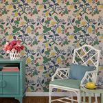 a white chair and green sideboard against a wall featuring colorful strawberry wallpaper.