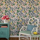 a white chair and green sideboard against a wall featuring colorful strawberry wallpaper.